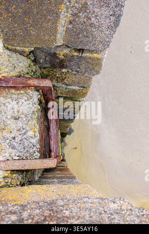 Old rusty ladder on a pier to the sand beach Stock Photo