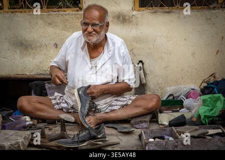 Elderly man repairing shoes on the streets of Jaipur, Rajasthan, India Stock Photo