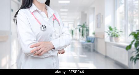 Confident doctor standing in hospital corridor with crossed arms, representing professionalism, healthcare service, and medical expertise Stock Photo