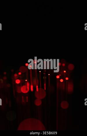 Dark background with red glowing fiber optic lights and soft bokeh effect, representing data transmission, digital networks, and cyber technology. Stock Photo