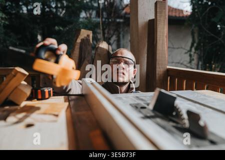Carpenter using a handheld circular saw at a table saw workbench during a home renovation project Stock Photo