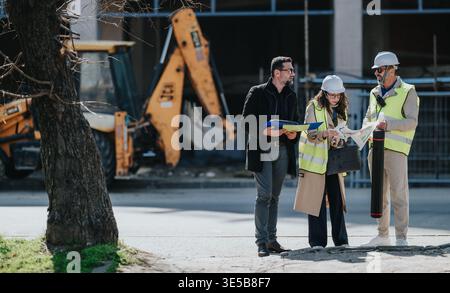 Construction engineers reviewing plans and inspecting site together during an urban building project Stock Photo