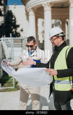 Construction engineer and architect reviewing blueprints during on-site inspection at a classical building Stock Photo