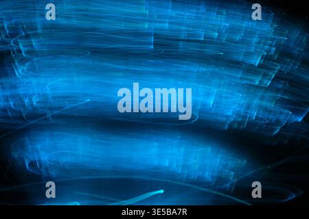 Abstract long exposure photography featuring horizontal blue and turquoise light trails against dark background, creating sense motion and energy Stock Photo