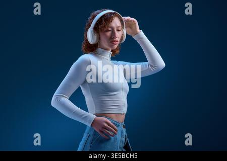 A curly haired redhead loses herself in the music at the studio, feeling the beat. Stock Photo