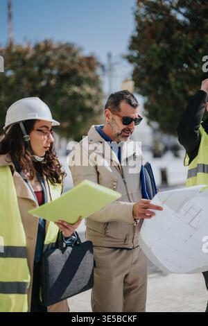 Construction team reviewing blueprint plans on site with engineers and architect consulting Stock Photo