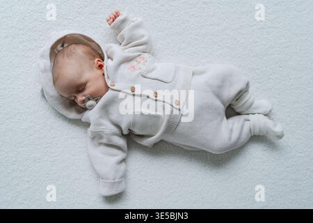 Infant lying on clean white background in minimal style. Simple and aesthetic baby portrait. Perfect for parenting, healthcare, and lifestyle concepts Stock Photo