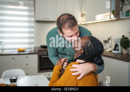 Multiethnic couple sharing kiss in home kitchen Stock Photo