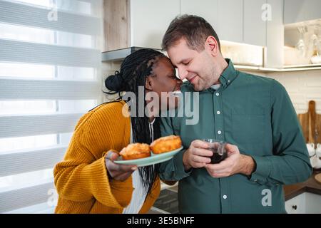 Interracial couple sharing happy morning with muffins and coffee Stock Photo