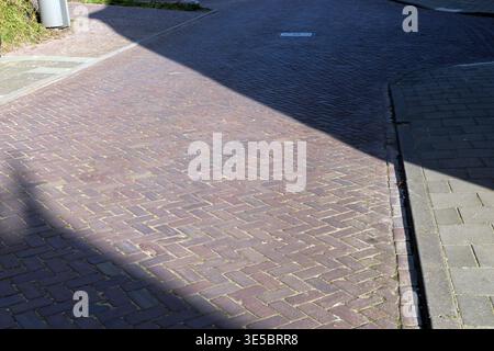 Sunlight and shadow creating geometric contrast on a paved brick surface in an urban outdoor setting. Stock Photo