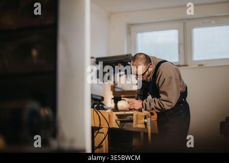 Craftsman working on wooden project in small woodworking workshop using hand tools and vise Stock Photo