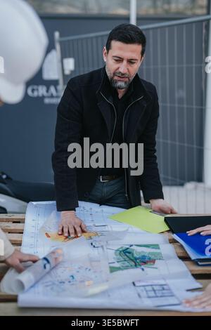 Construction engineers reviewing blueprints at an outdoor site meeting with project plans Stock Photo