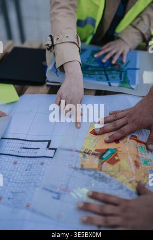 Construction engineers reviewing architectural blueprints and site plans together on a work table Stock Photo