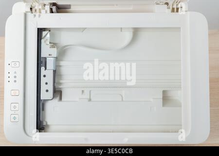 Flatbed scanner bed inside a multifunction office printer shown from above. Clean empty glass surface, control buttons and mechanism visible, document Stock Photo