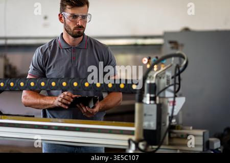 Male engineer setup plasma cutter for work in metalwork workshop. Stock Photo