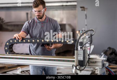 Male engineer setup plasma cutter for work in metalwork workshop. Stock Photo