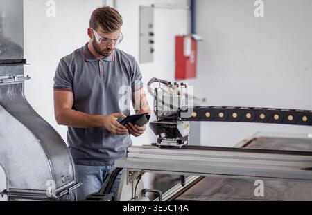 Male engineer setup plasma cutter for work in metalwork workshop. Stock Photo