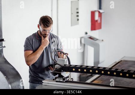 Male engineer setup plasma cutter for work in metalwork workshop. Stock Photo
