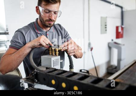 Male engineer setup plasma cutter for work in metalwork workshop. Stock Photo