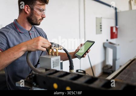 Male engineer setup plasma cutter for work in metalwork workshop. Stock Photo