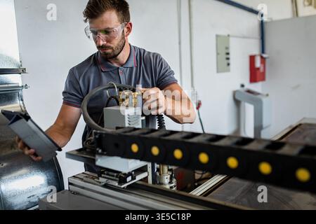 Male engineer setup plasma cutter for work in metalwork workshop. Stock Photo