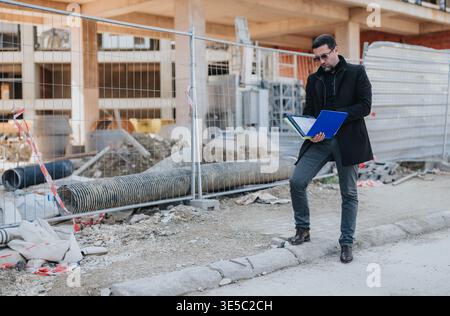 Construction engineer reviewing plans at an urban building site during on-site inspection Stock Photo