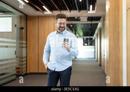 Man in smart casual attire using a mobile phone, smiling while interacting with technology for business communication and networking in a contemporary Stock Photo