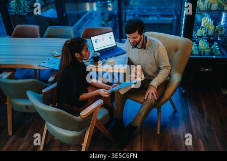 Business discussion between colleagues over coffee and laptop in a modern casual meeting space Stock Photo