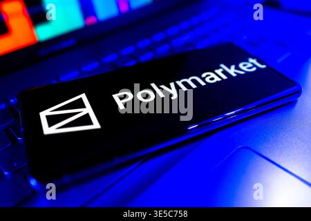 Polymarket Prediction Market App Logo Displayed On Mobile Phone Screen With Desktop Computer And Financial Performance Chart Background Stock Photo