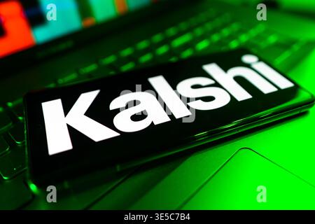 Kalshi Prediction Market App Logo Displayed On Mobile Phone Screen With Desktop Computer And Financial Performance Chart Background Stock Photo