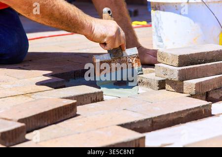 Contractor applies mortar with trowel while arranging bricks on construction site Stock Photo