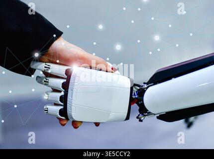 Advanced bionic robotic hand shaking hands with human, symbolizing AI and human collaboration. Stock Photo