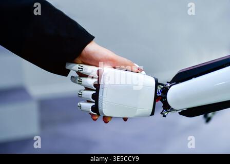 Advanced bionic robotic hand shaking hands with human, symbolizing AI and human collaboration. Stock Photo