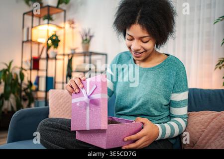 Happy young adult woman opening a surprise gift box Stock Photo
