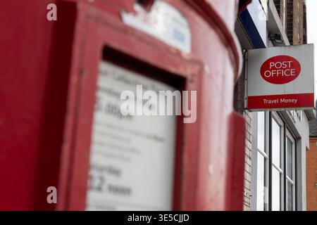 Close-up of a post office sign on an English high street, with a post box in the foreground.  This picture taken in Willesden, London NW10 Stock Photo