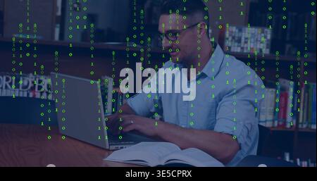 Typing man in blue shirt, glasses at library using silver laptop, textbook with green code overlay Stock Photo