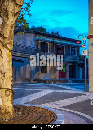 Wuhan, China - June 18, 2025: Renovated two-story brick building with balconies and a large tree in a paved pedestrian plaza at dusk. The image captur Stock Photo