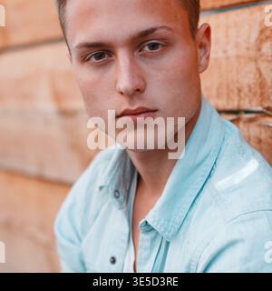 Close-up portrait of a handsome young guy in denim clothes with freckles Stock Photo