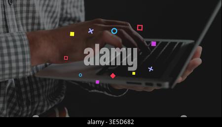 Typing man wearing checked shirt, hands pressing keys on silver laptop in studio with bright icons Stock Photo