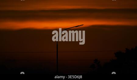 The sunset is behind the wires of the street lights Stock Photo