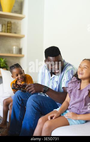 Playing African American family laughing on white couch in living room, with game controller Stock Photo