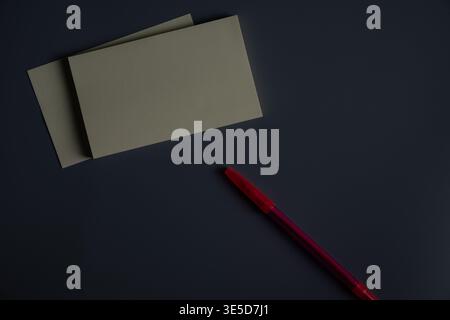 Stack of blank yellow sticky notes with red pen on dark background. Minimal workspace scene with copy space, concept of planning, reminders and organi Stock Photo