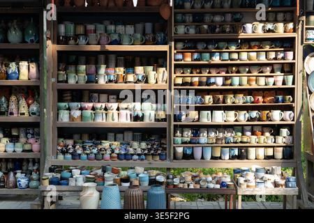 Hoi An, Vietnam - February 2026: Colorful handmade ceramic cups and pottery displayed on wooden shelves at local craft shop Stock Photo