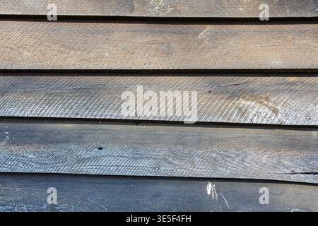 Weathered wooden siding with horizontal planks, visible grain, knots and nail holes; rustic exterior texture perfect for backgrounds, design mockups, Stock Photo