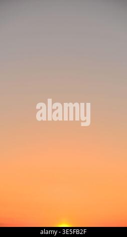 Dusk over the ocean, with colours fading from orange-yellow to the grey of the sky. Stock Photo