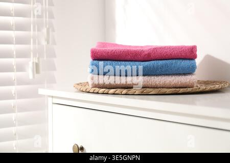 Stack of colorful towels on white dresser indoors Stock Photo