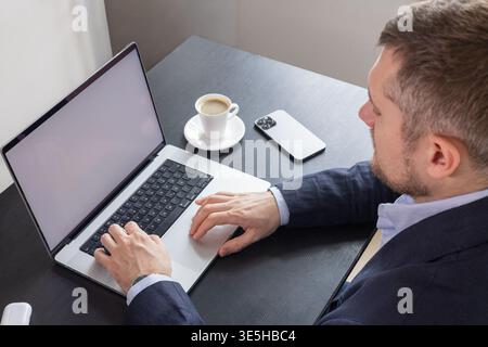 Overhead view of businessman working on laptop with coffee and phone on minimalist desk Stock Photo