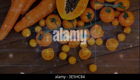 Showing amber cherry tomatoes on vine on kitchen board with halved papaya seeds and carrots Stock Photo