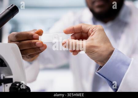 Close up shot of laboratory technicians team inspecting specimen slide for microscopy study. Teamworking lab scientists review cytology slide for clinical testing procedure Stock Photo