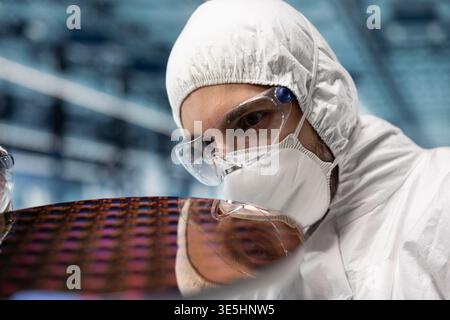 Close up of man inspecting microelectronic silicon wafer components in smart factory. Worker verifying semiconductor substrate integrated circuits quality in futuristic foundry Stock Photo